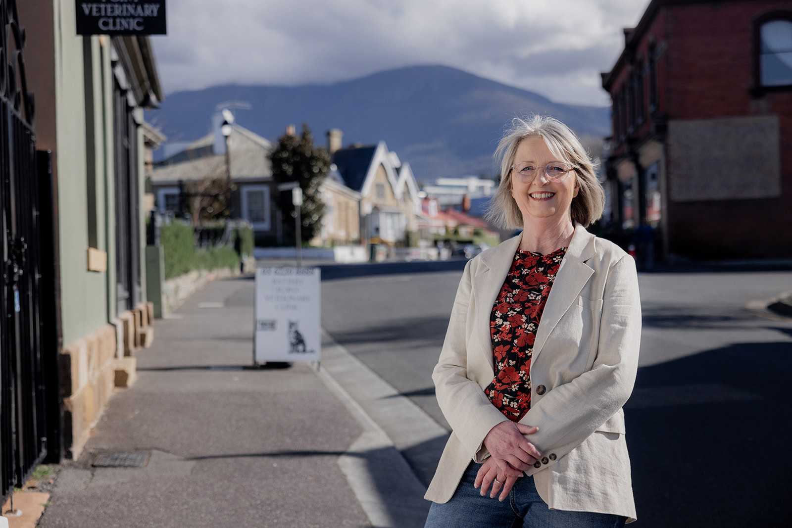 Mary Figg standing on a Hobart street with kunanyi/Mt Wellington in the background