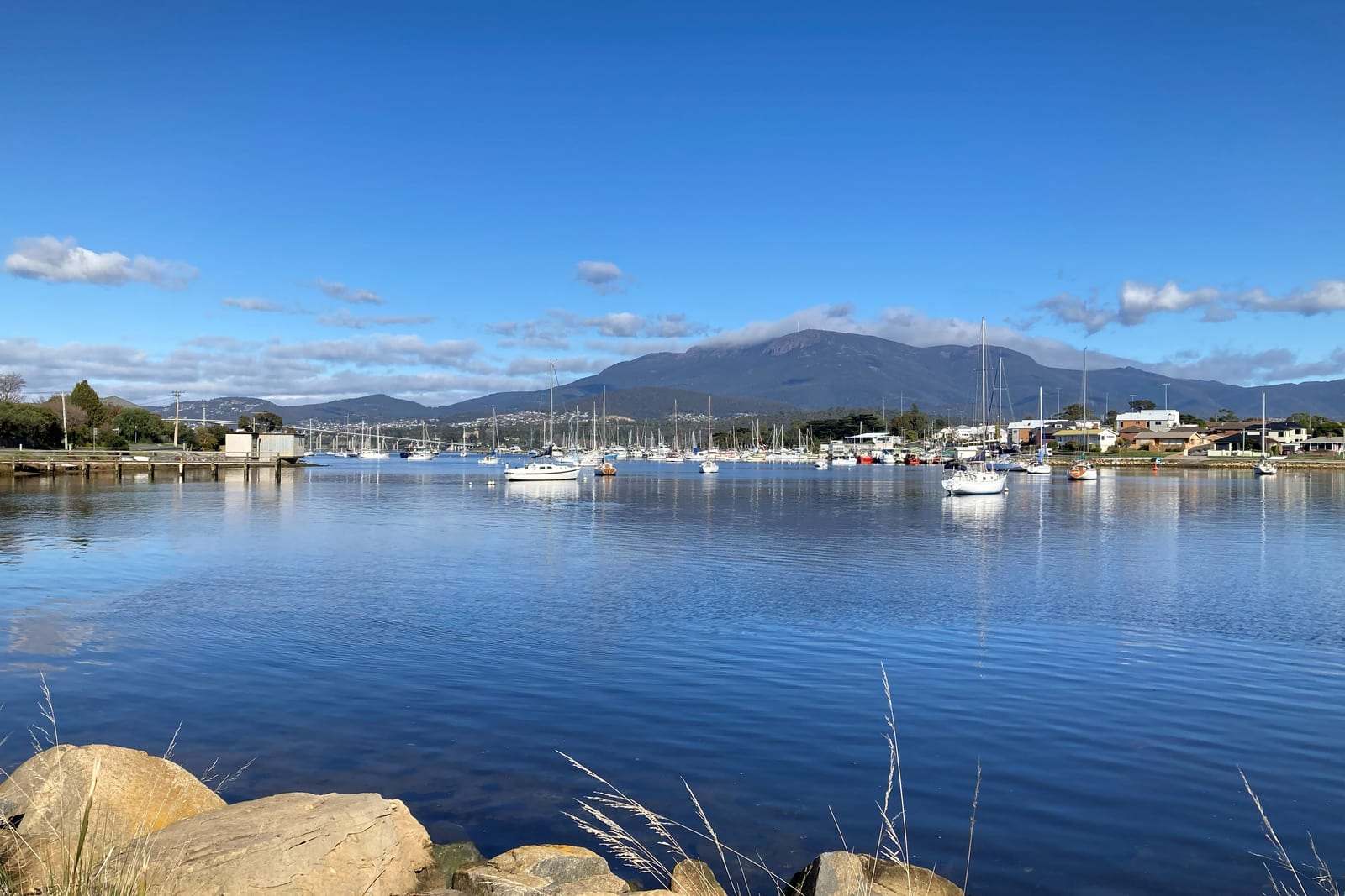 Yachts moored on the Derwent River with kunanyi/Mount Wellington and its cloud cap behind