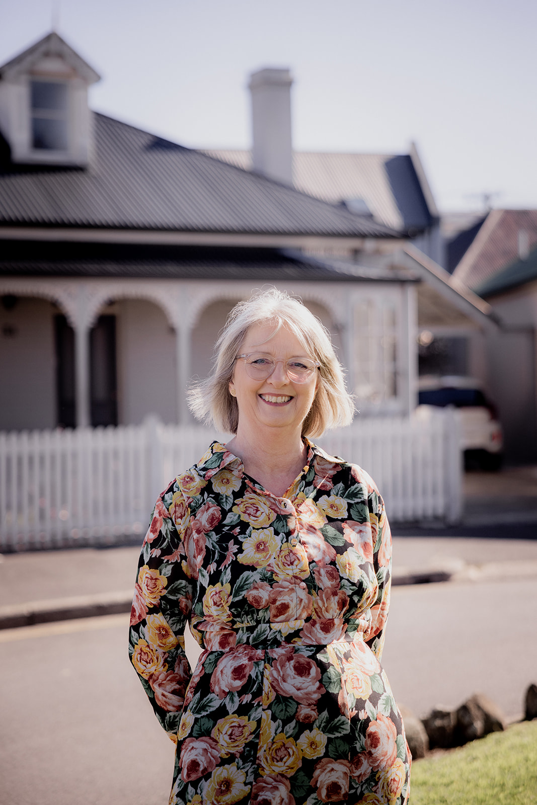 Mary Figg smiling on a heritage Hobart street, kunanyi/Mt Wellington in the distance